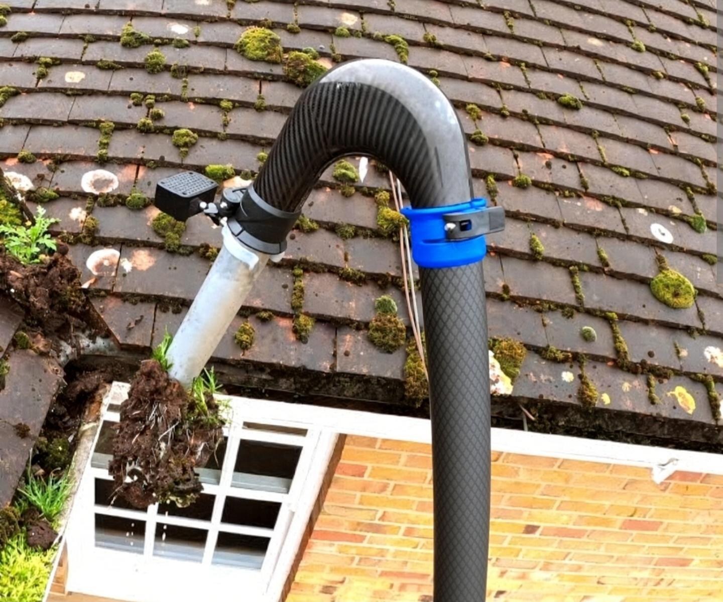 Vacuum pole lifting a clump of debris from a gutter.